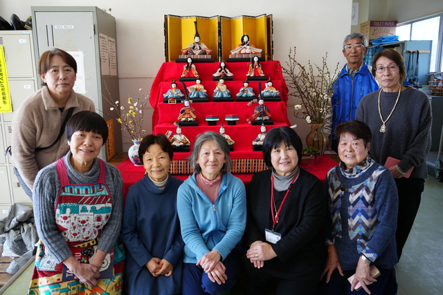 制作に携わった方や校長先生・寄附者がひな人形を囲んで微笑む様子