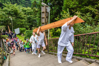 大きな木太刀を担いで大山詣りをする写真