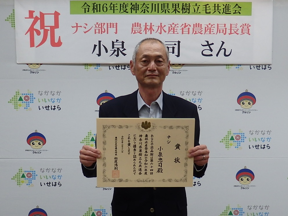 表彰状を手にする小泉忠司さんの子の和明さん